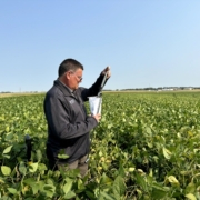 A Trace Genomics scientist stands in a verdant field testing soil samples using a probe lubricated with eco-friendly oils