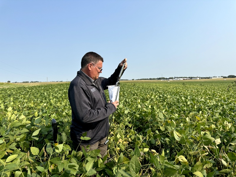 A Trace Genomics scientist stands in a verdant field testing soil samples using a probe lubricated with eco-friendly oils